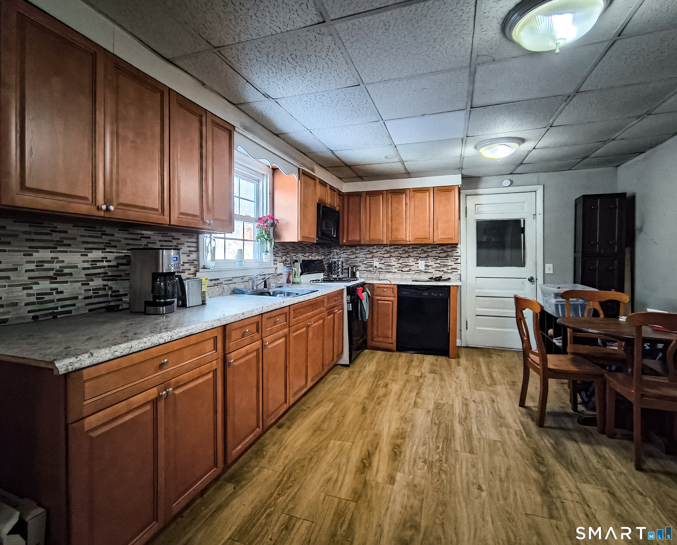 70 Walnut Street Putnam, CT 06260 - Photo 12 of 20 a kitchen with stainless steel appliances granite countertop wooden floors a stove a sink dishwasher a dining table and chairs with wooden floor