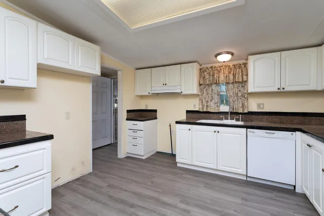 a kitchen with granite countertop white cabinets and white appliances