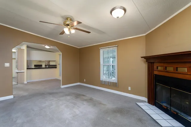 a view of an empty room with a kitchen and a window