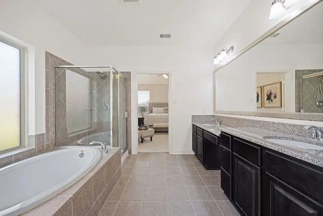 a spacious bathroom with a granite countertop tub sink shower and mirror