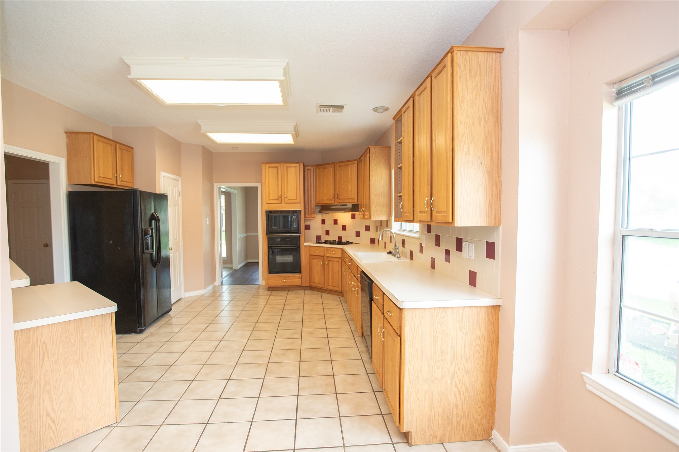8615 Mile Run Road Humble, TX 77346 - Photo 12 of 16 a large white kitchen with a sink a refrigerator and a window