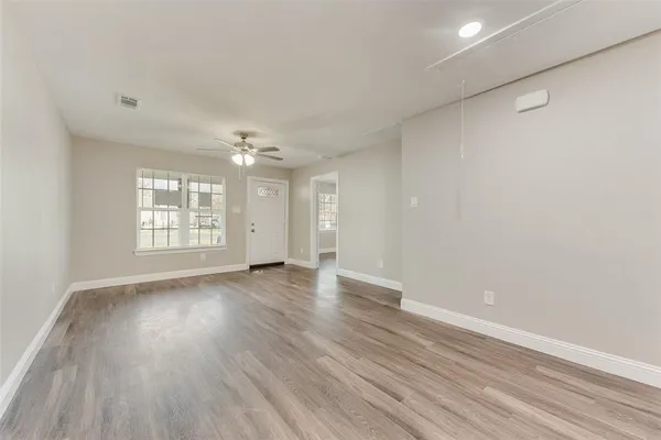 a view of an empty room with wooden floor and a window