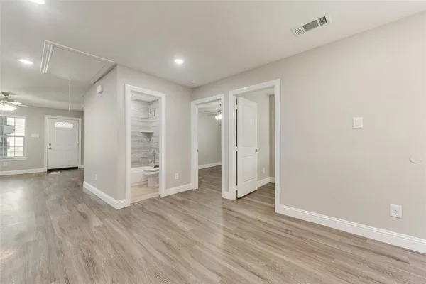 an empty room with wooden floor & windows and bathroom