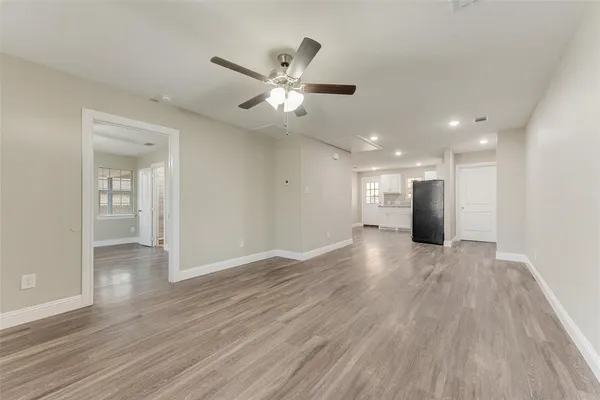 a view of an empty room with wooden floor and a ceiling fan