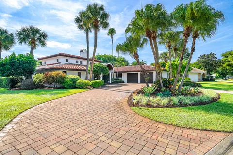 a front view of a house with a garden and palm trees