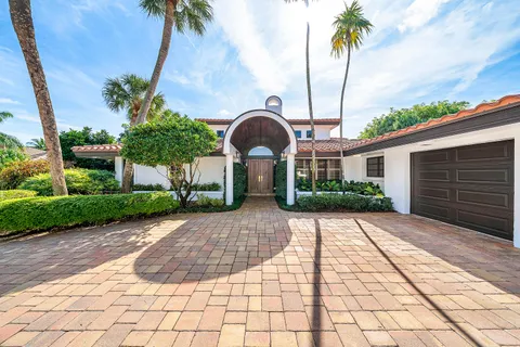 a front view of a house with garden and palm tree