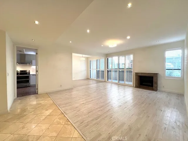 an empty room with wooden floor fireplace and windows