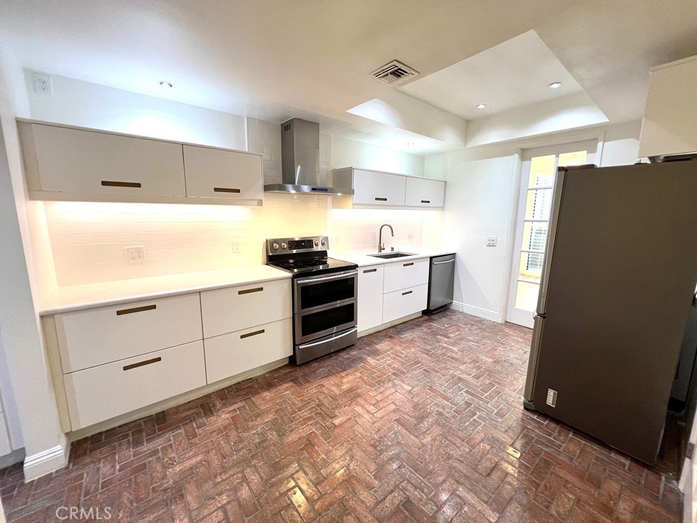 700 South Lake Avenue, Unit 111 Pasadena, CA 91106 - Photo 17 of 40 a kitchen with stainless steel appliances a stove a refrigerator and white cabinets