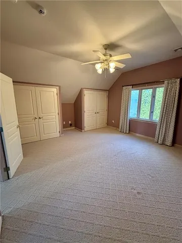 an empty room with chandelier fan and windows
