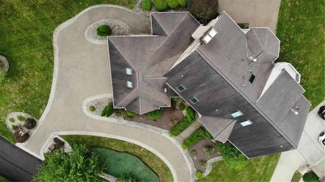 an aerial view of a house with a yard and trees all around