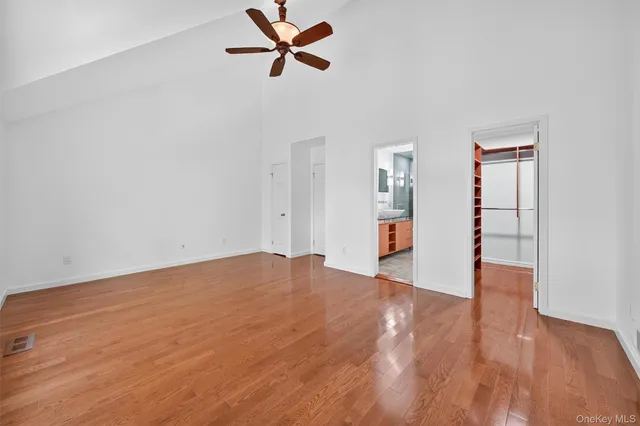 a view of empty room with wooden floor and ceiling fan