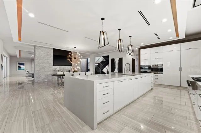 a large white kitchen with a large window a sink and a stove top oven