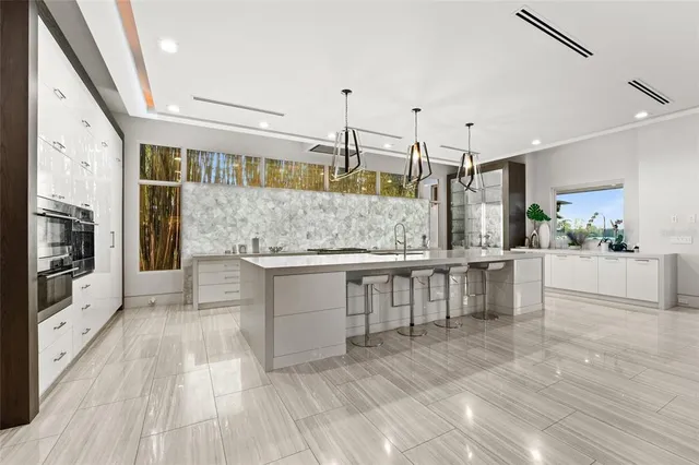 a large white kitchen with kitchen island a stove a sink dishwasher and microwave oven with wooden floor