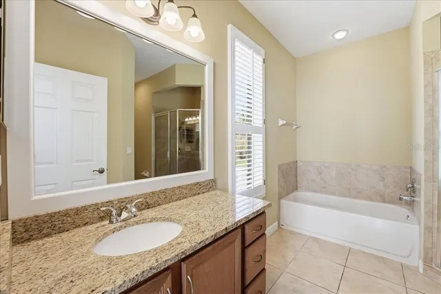 a bathroom with a granite countertop sink a mirror and a bathtub