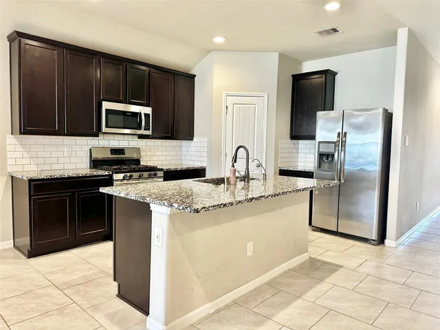 a kitchen with stainless steel appliances granite countertop a stove a refrigerator and a sink