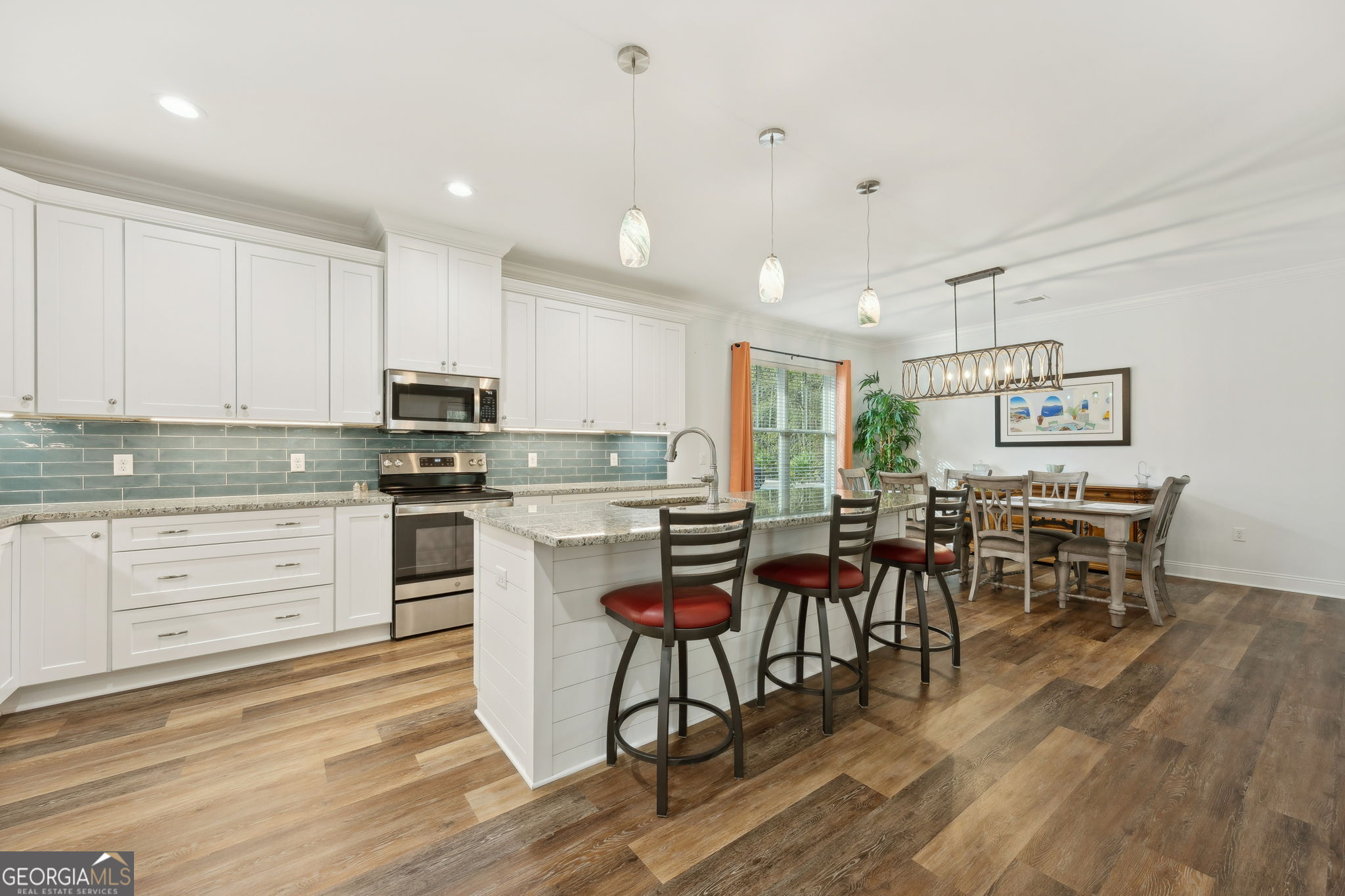 212 Placid Road St. Marys, GA 31558 - Photo 16 of 75 a kitchen with stainless steel appliances kitchen island granite countertop a table chairs stove and white cabinets