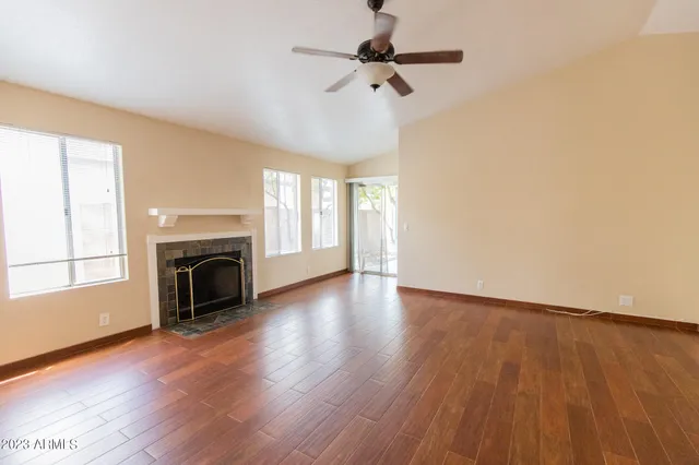 an empty room with wooden floor fireplace and windows