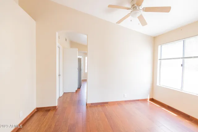a view of an empty room with wooden floor and a window