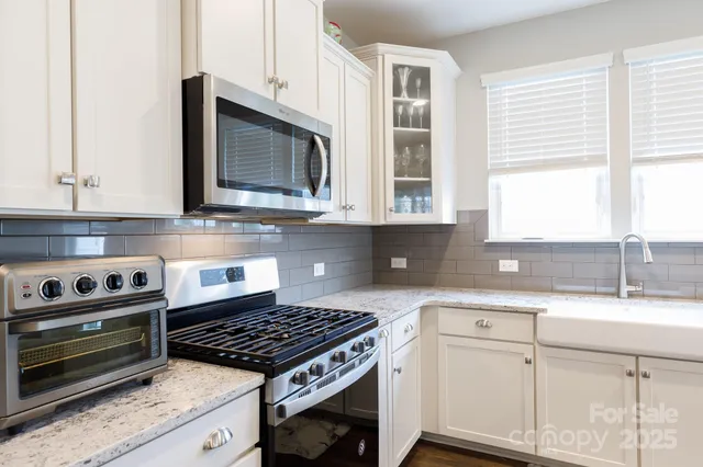 a kitchen with granite countertop a stove a sink and a microwave