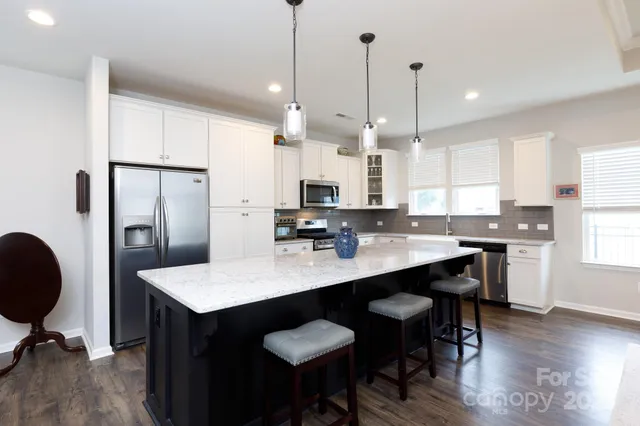 a kitchen with stainless steel appliances granite countertop a table chairs sink refrigerator and cabinets