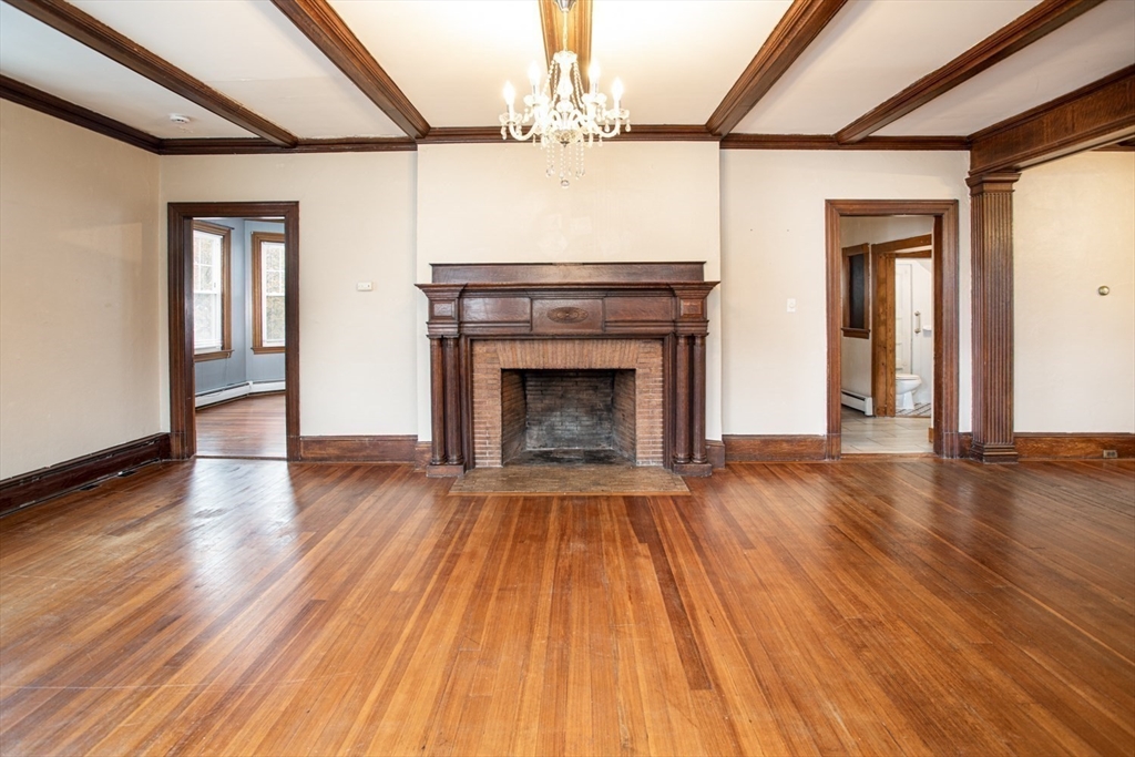 a view of an empty room with wooden floor fireplace and a window