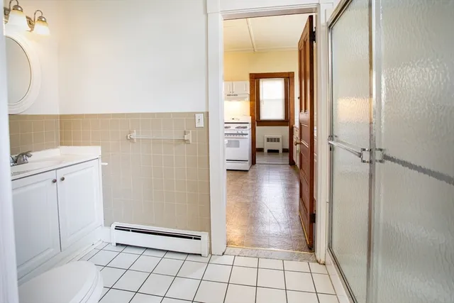 a view of a hallway with wooden floor and a bathroom