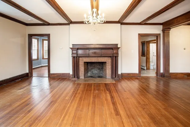 a view of an empty room with wooden floor fireplace and a window