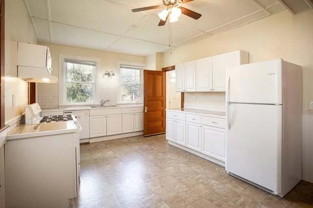 a kitchen with a refrigerator a sink and dishwasher with white cabinets