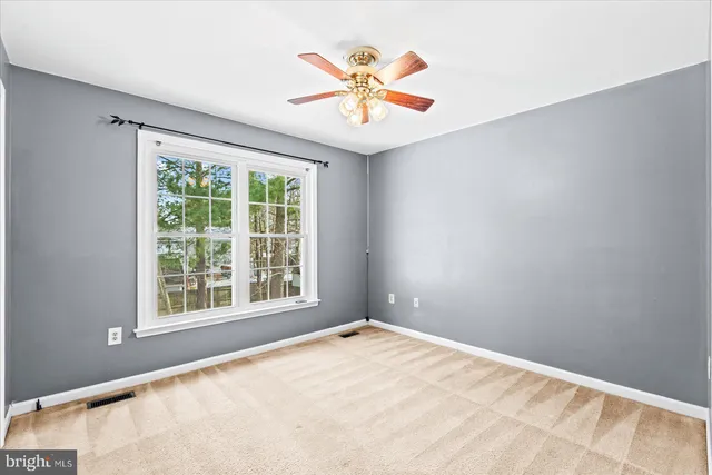 an empty room with window and ceiling fan