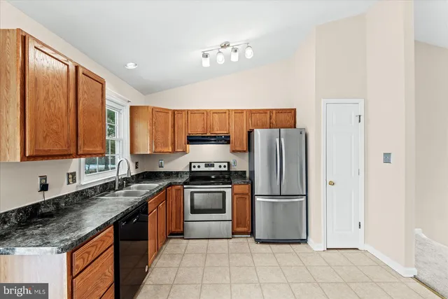 a kitchen with stainless steel appliances granite countertop a stove top oven a sink and dishwasher