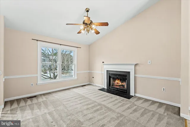 a view of an empty room with chandelier fan and fire place