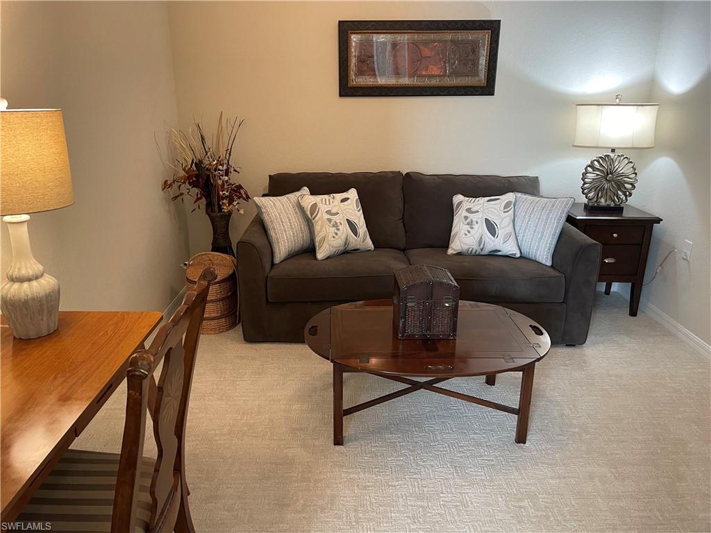 9727 Acqua Court, Unit 421 Naples, FL 34113 - Photo 11 of 26 a living room with furniture and a lamp