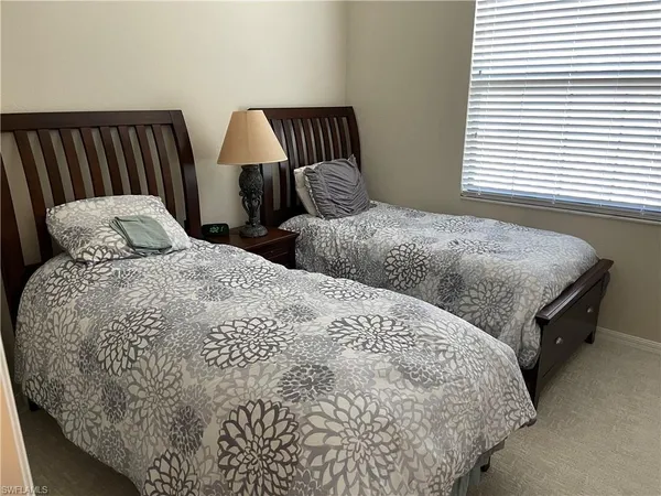 a bedroom with two beds and a lamp on dresser