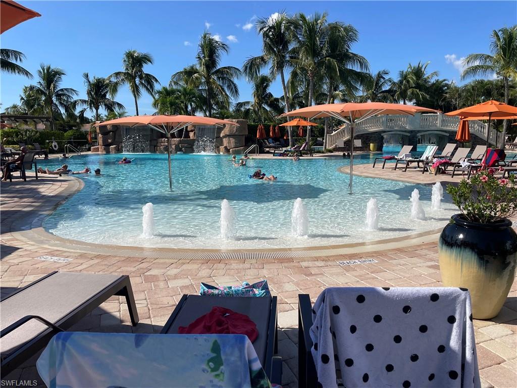 9727 Acqua Court, Unit 421 Naples, FL 34113 - Photo 23 of 26 a view of a patio with table and chairs potted plants and palm trees