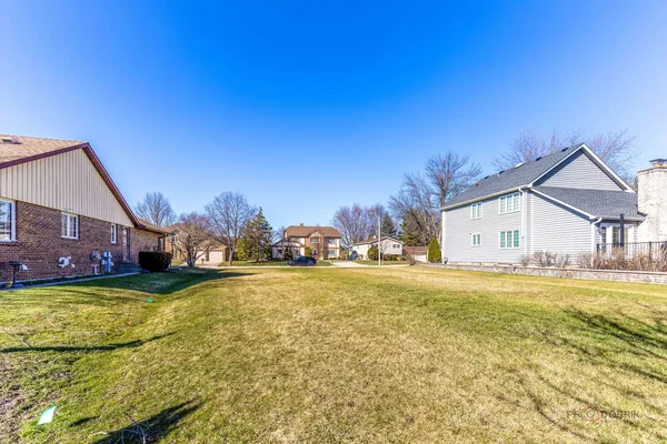 a view of a house with a yard and a large tree
