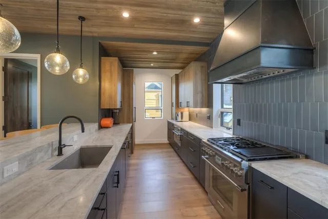 a kitchen with stainless steel appliances granite countertop a sink a stove and a wooden floors