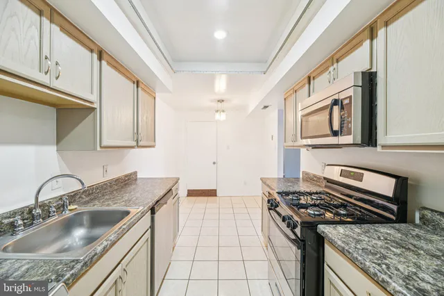 a kitchen with granite countertop a sink stove top oven and cabinets