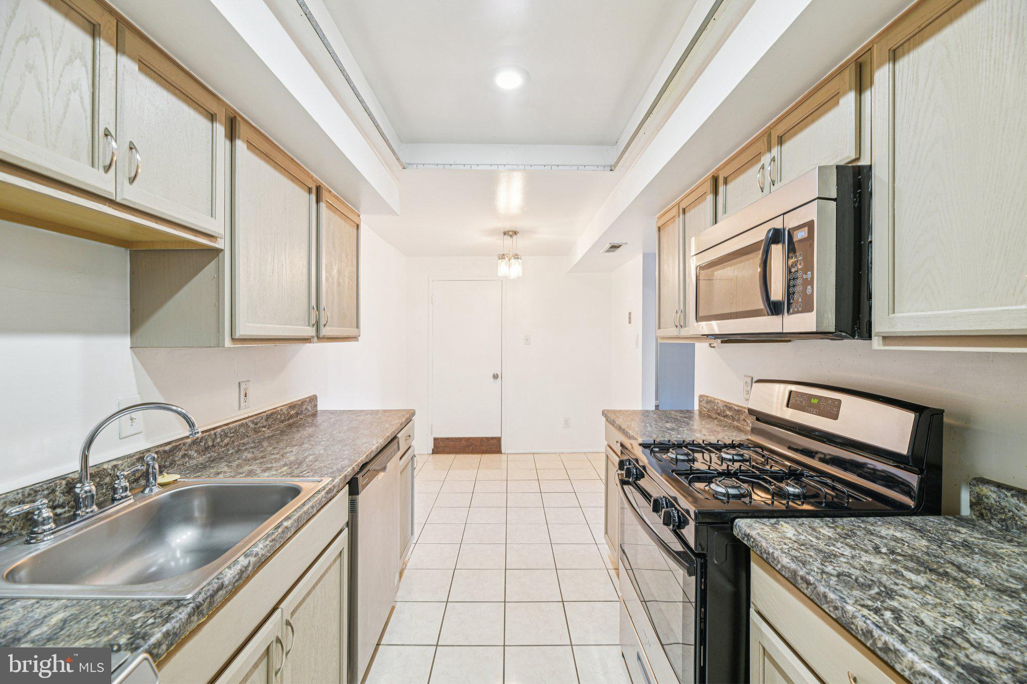 10216 Prince Place, Unit 9202 Upper Marlboro, MD 20774 - Photo 12 of 32 a kitchen with granite countertop a sink stove top oven and cabinets