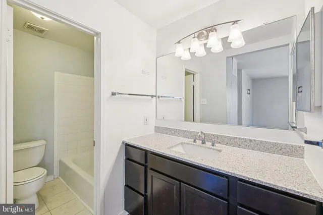 a bathroom with a granite countertop sink a toilet and a mirror