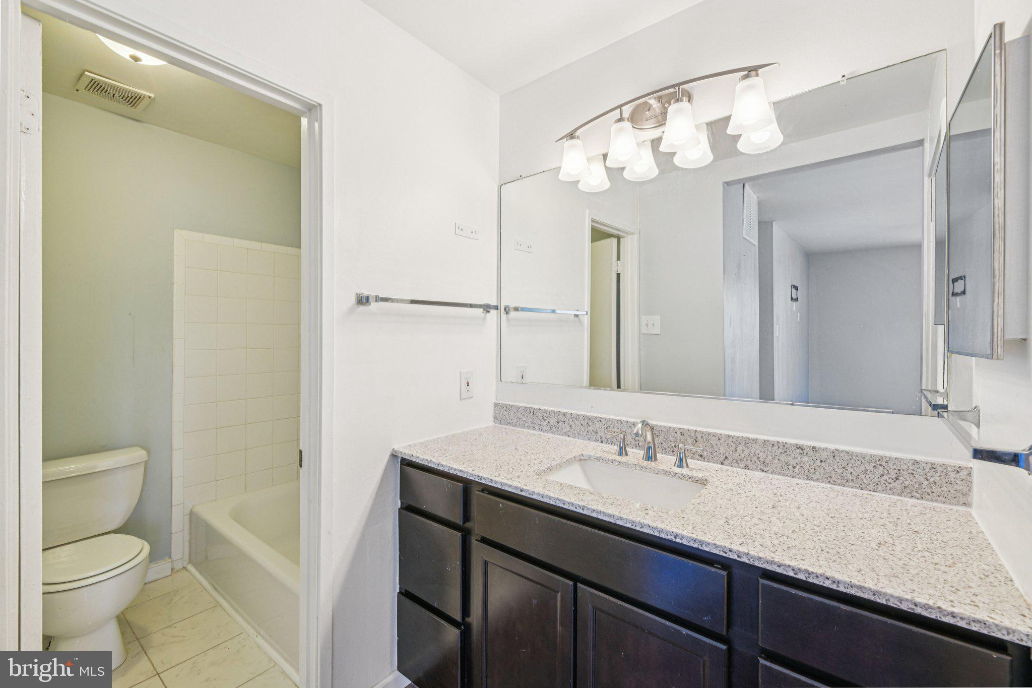 10216 Prince Place, Unit 9202 Upper Marlboro, MD 20774 - Photo 15 of 32 a bathroom with a granite countertop sink a toilet and a mirror