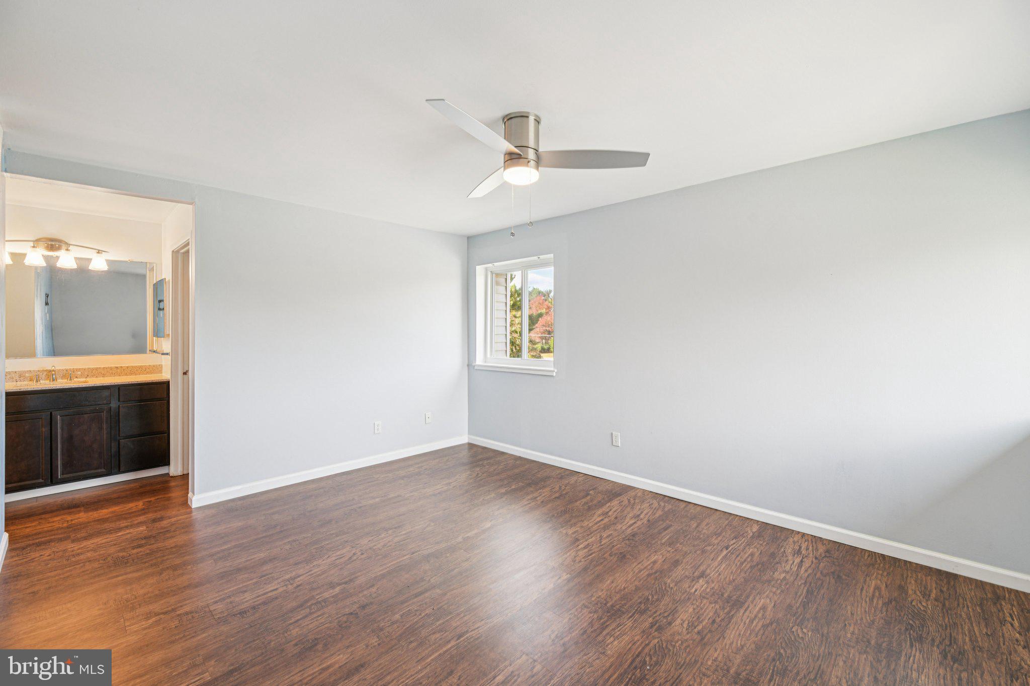 10216 Prince Place, Unit 9202 Upper Marlboro, MD 20774 - Photo 19 of 32 an empty room with wooden floor ceiling fan and windows