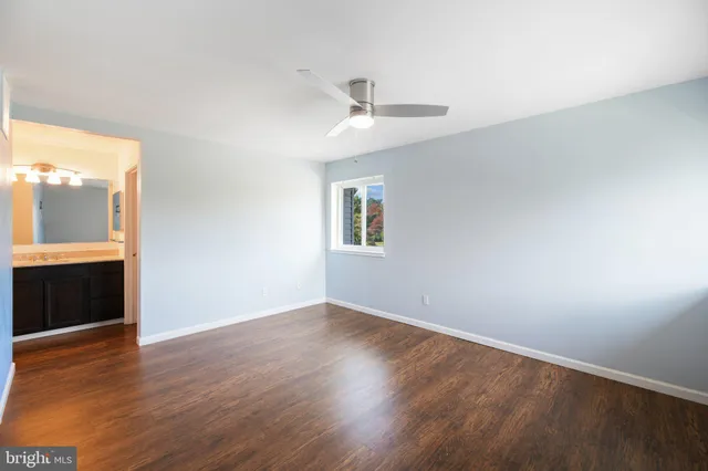 an empty room with wooden floor cabinet and windows