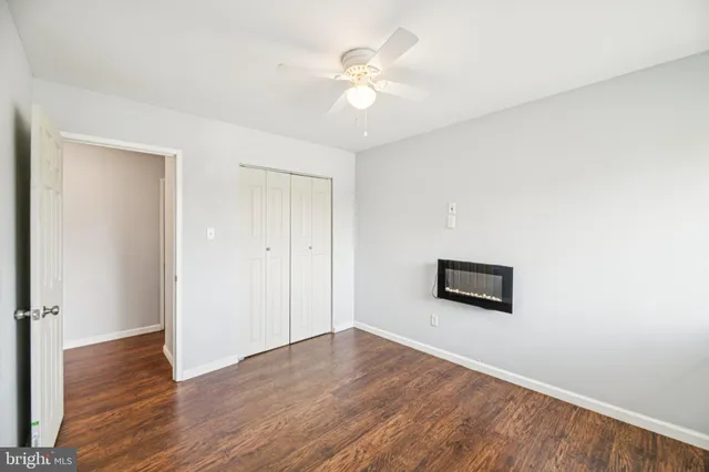 an empty room with wooden floor and ceiling fan