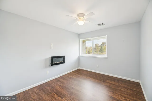an empty room with wooden floor chandelier fan and windows