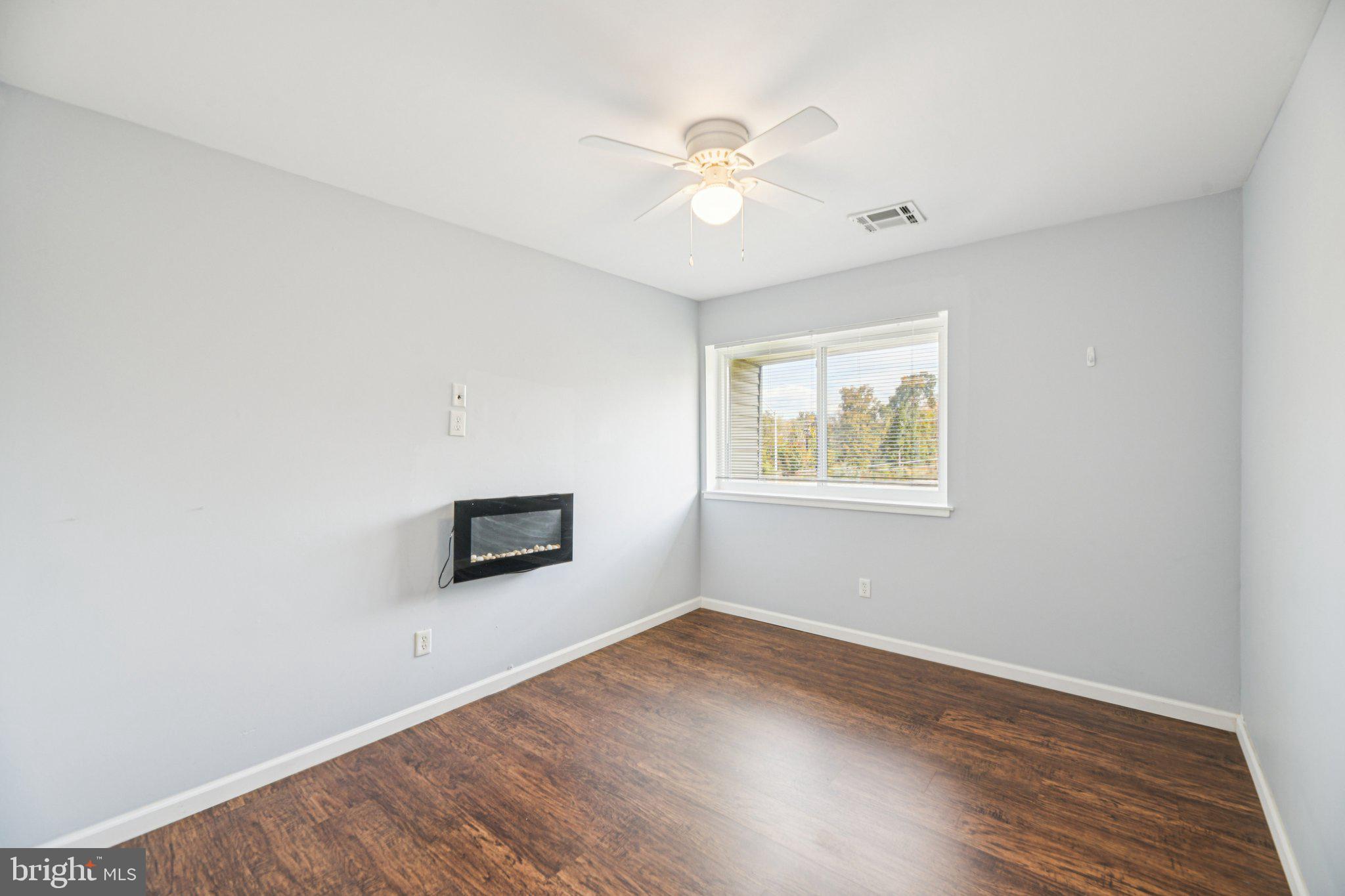 10216 Prince Place, Unit 9202 Upper Marlboro, MD 20774 - Photo 24 of 32 an empty room with wooden floor chandelier fan and windows