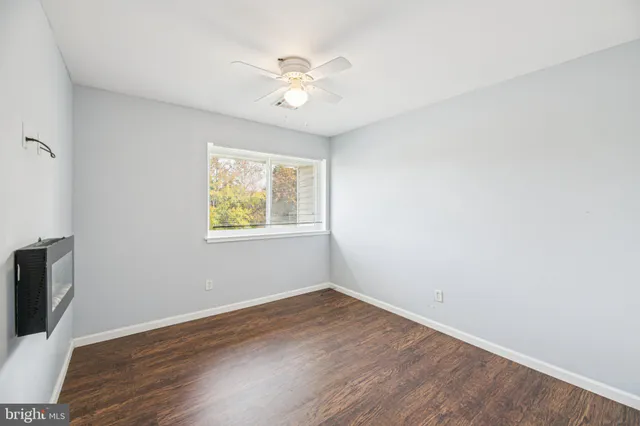 an empty room with wooden floor chandelier fan and windows
