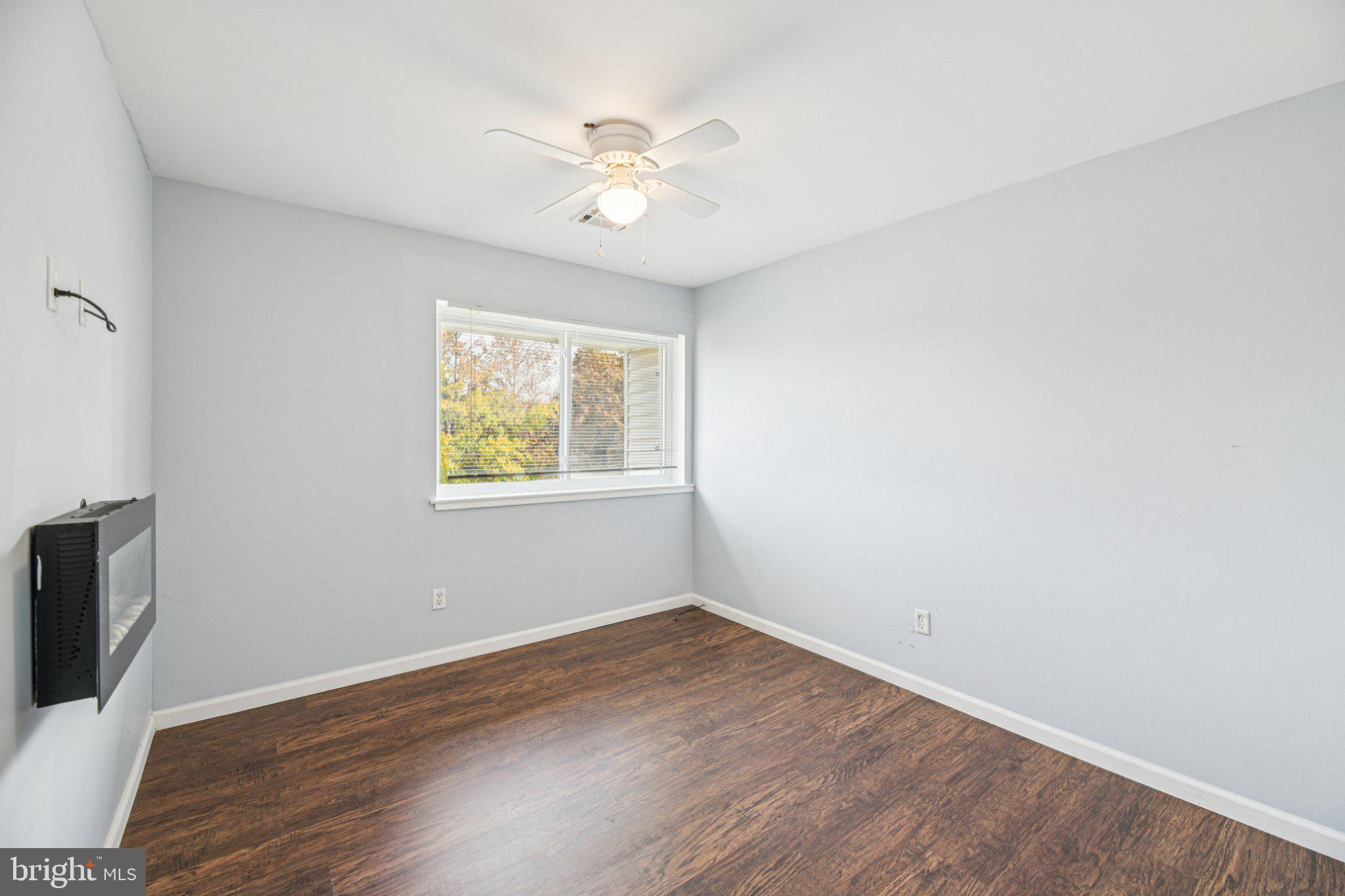 10216 Prince Place, Unit 9202 Upper Marlboro, MD 20774 - Photo 26 of 32 an empty room with wooden floor chandelier fan and windows