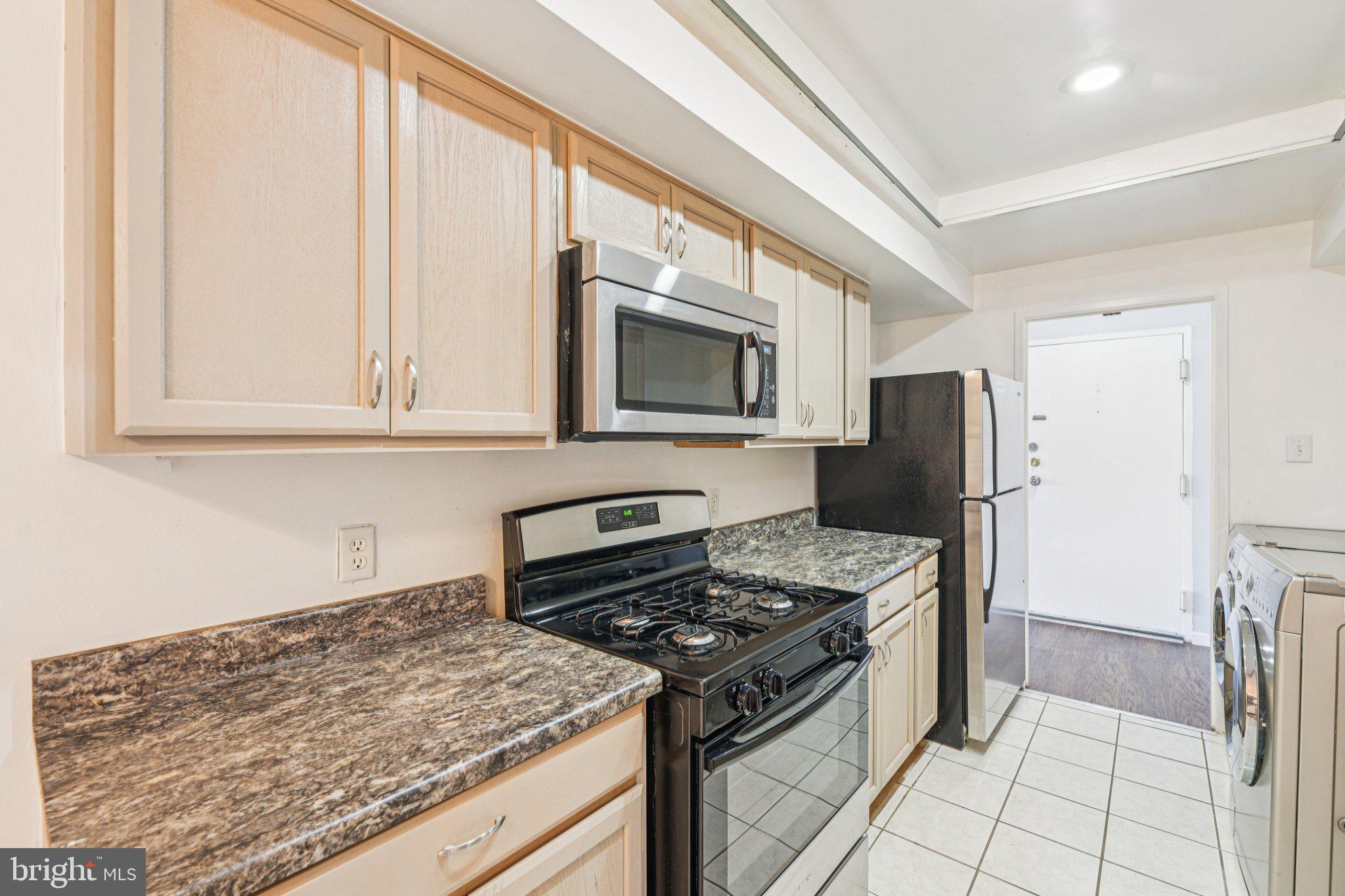 10216 Prince Place, Unit 9202 Upper Marlboro, MD 20774 - Photo 9 of 32 a kitchen with stainless steel appliances granite countertop a stove microwave and refrigerator