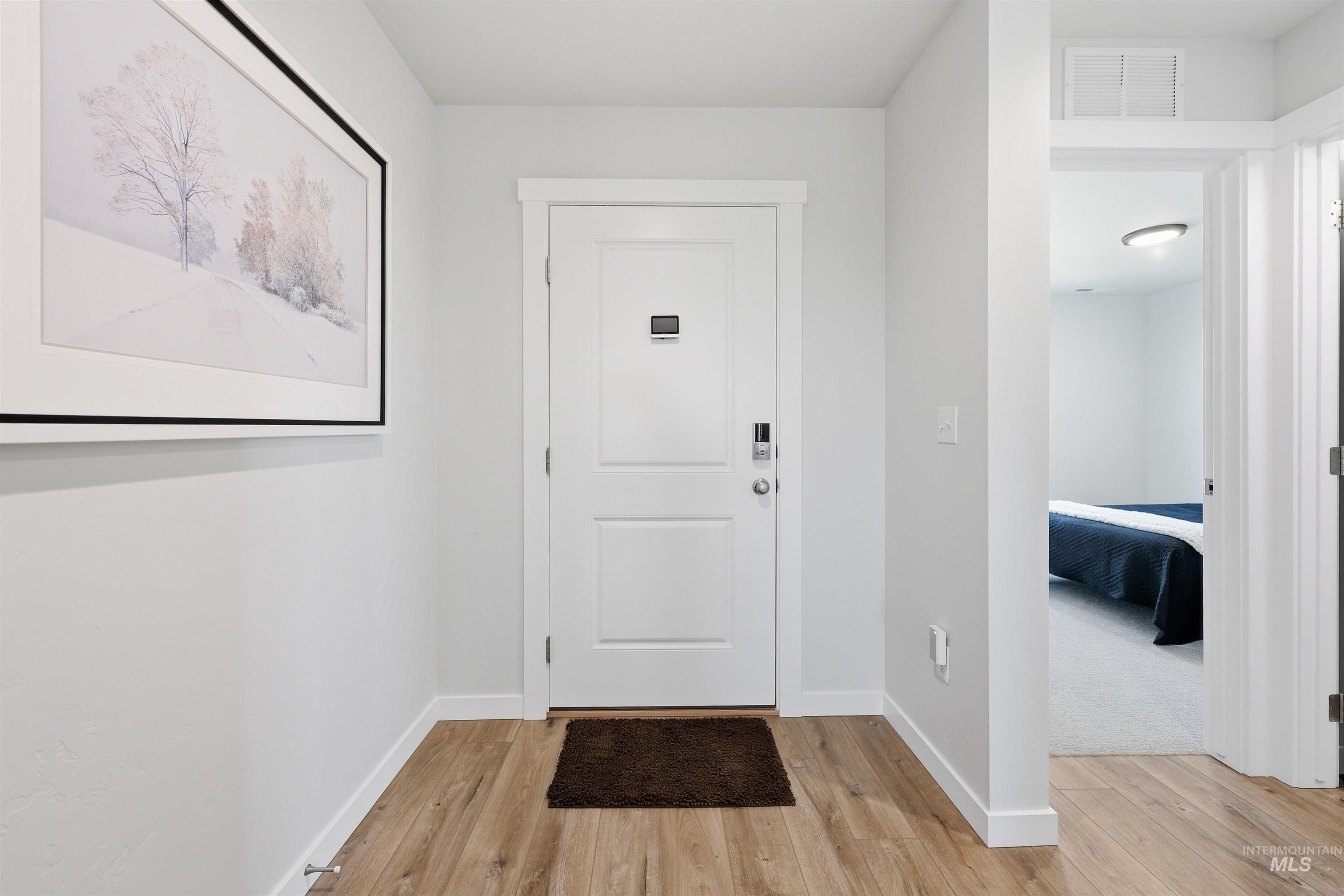 3811 West Maypearl Street Meridian, ID 83642 - Photo 5 of 39 Entryway featuring wood-finish flooring, white trim, and a white paneled door with contemporary hardware
