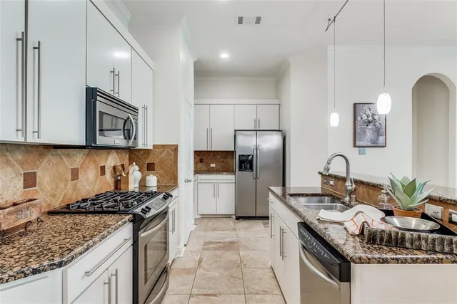 a kitchen with granite countertop a sink stove and refrigerator